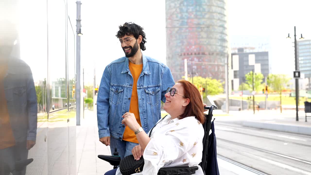 Uomo che assiste una donna su una sedia a rotelle in un ambiente urbano