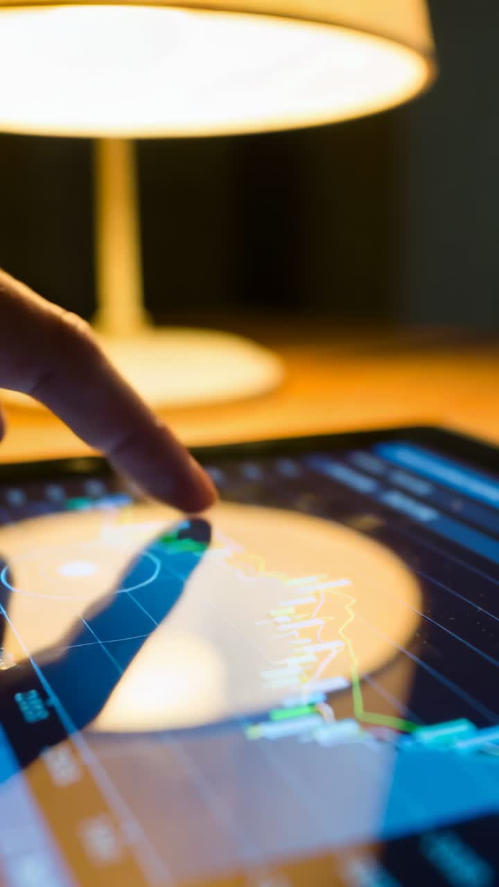 Vertical video: Tapping index fingertip checking tablet charts, tuning controls under lamp on desk