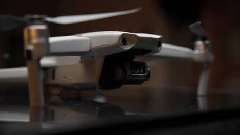 video cinematográfico de primer plano de un dron iluminado con una luz suave desde arriba y luces naranjas en el fondo, filmado en 4k con movimiento de cámara