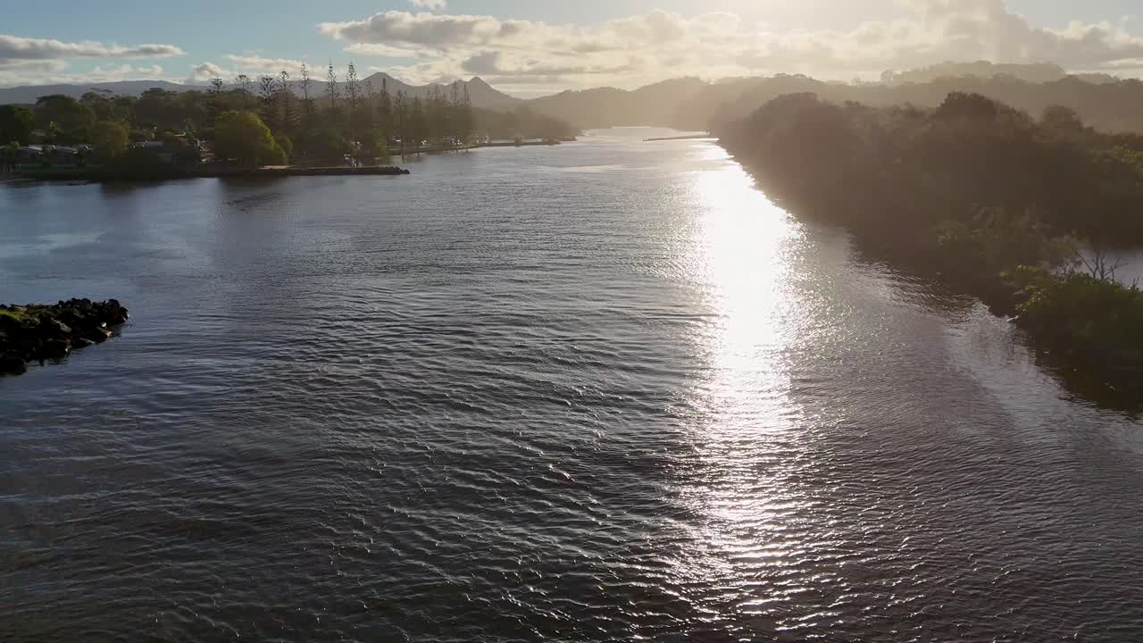 Drone captures serene sunset views over Brunswick Heads river, highlighting tranquil waters and lush surroundings with golden light reflections