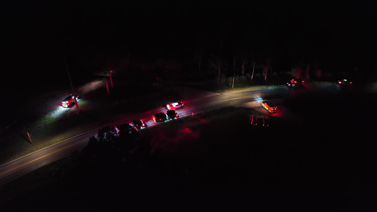 Fire trucks and emergency vehicles arriving accident scene at night. Rural american interstate road. Aerial top down shot. Flashing lights of vehicles.
