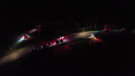 fire trucks and emergency vehicles arriving accident scene at night. rural american interstate road. aerial top down shot. flashing lights of vehicles.