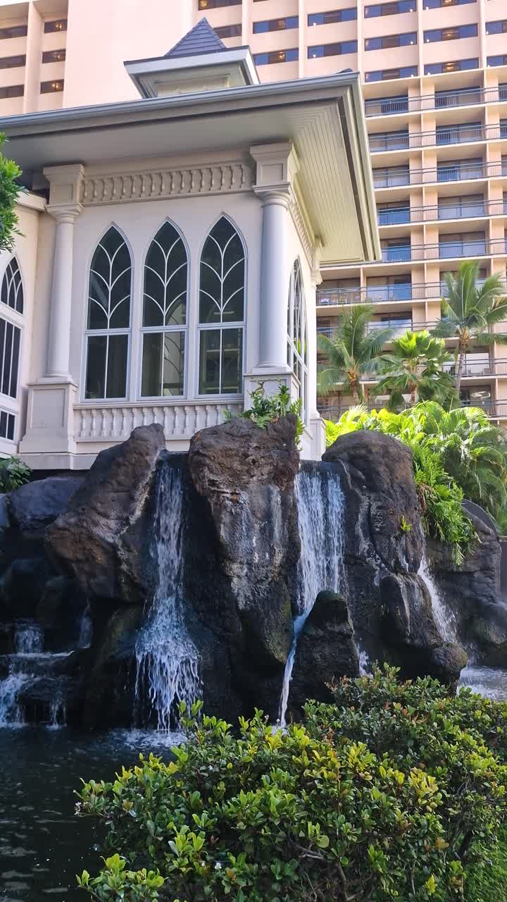 Vista vertical de una cascada artificial y el exterior de un resort de lujo en Honolulu, Hawái, EE. UU.