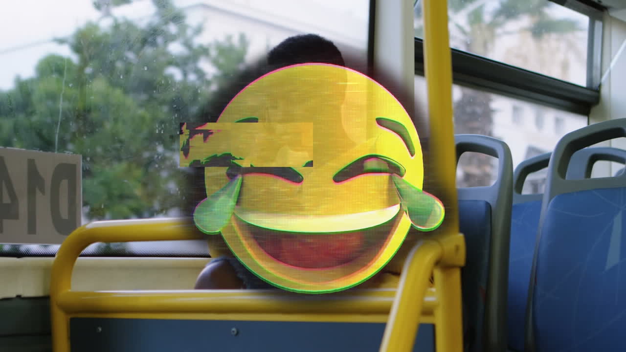 Glitch effect over laughing face emoji against african american woman using smartphone in the bus
