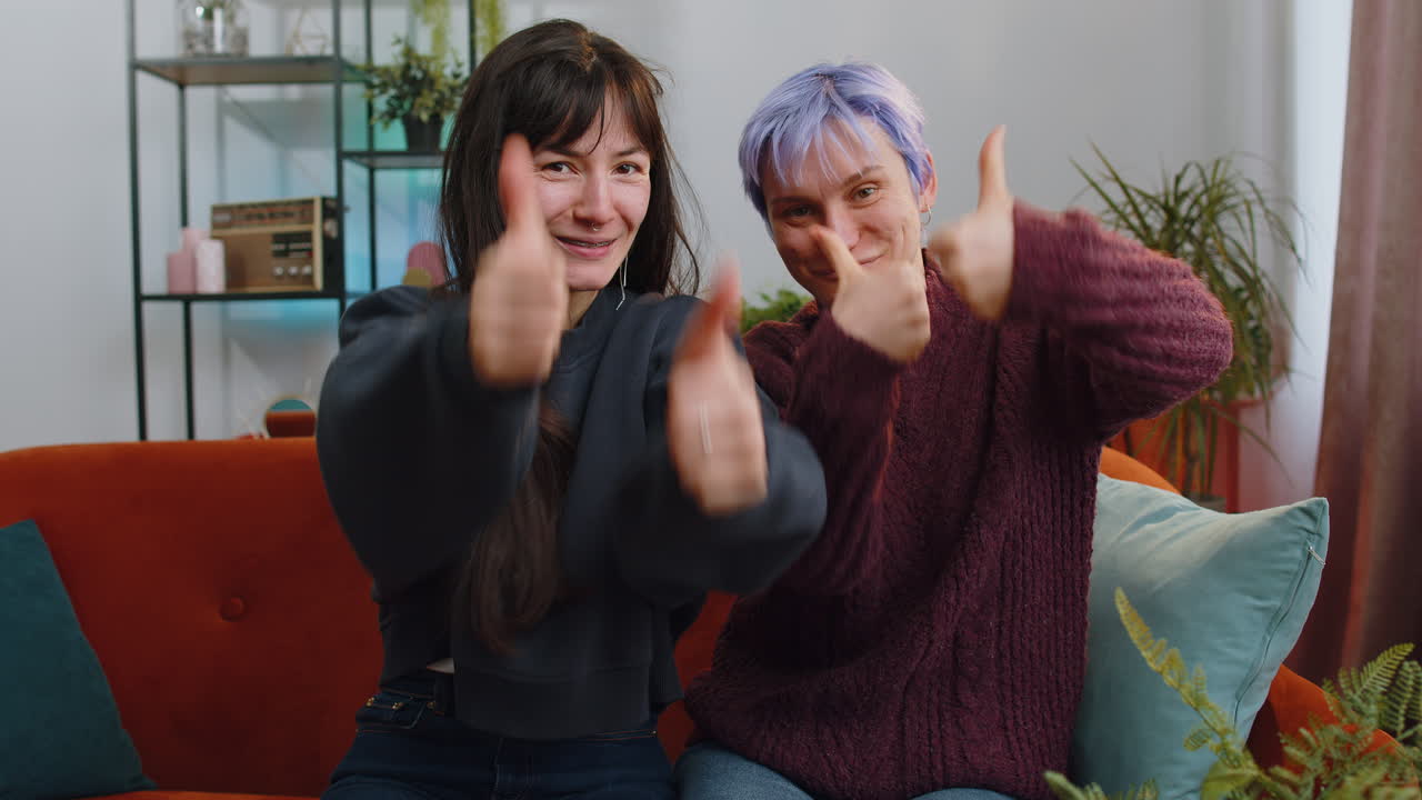 Happy lesbian women family couple showing thumbs up like sign positive something good feedback home