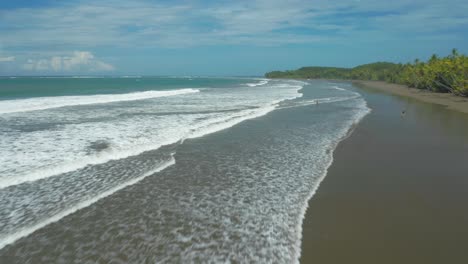 long rolling waves breaking in shallow water of uvita beach, costa rica