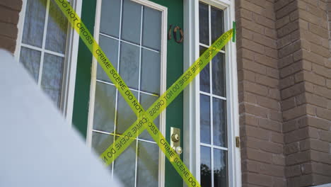 Yellow-crime-scene-do-not-cross-tape-across-front-door-of-house