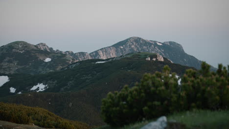 a shot of mountain peca, thin clouds above, early morning light, patches of snow on the mountains