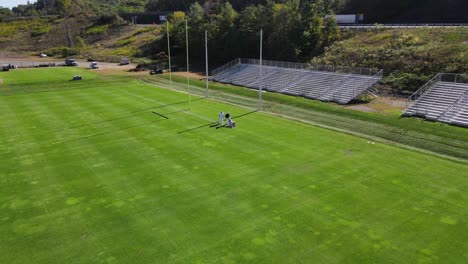 toma aérea de líneas de pintura de la tripulación en la zona final de un campo de fútbol de césped durante el verano