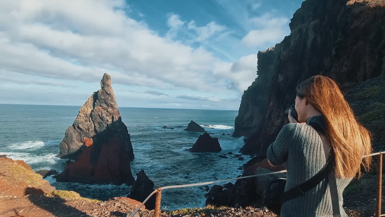 Ponta de São Lourenço, Madeira: female traveler photographing a stunning volcanic cliff coastline in Portugal
