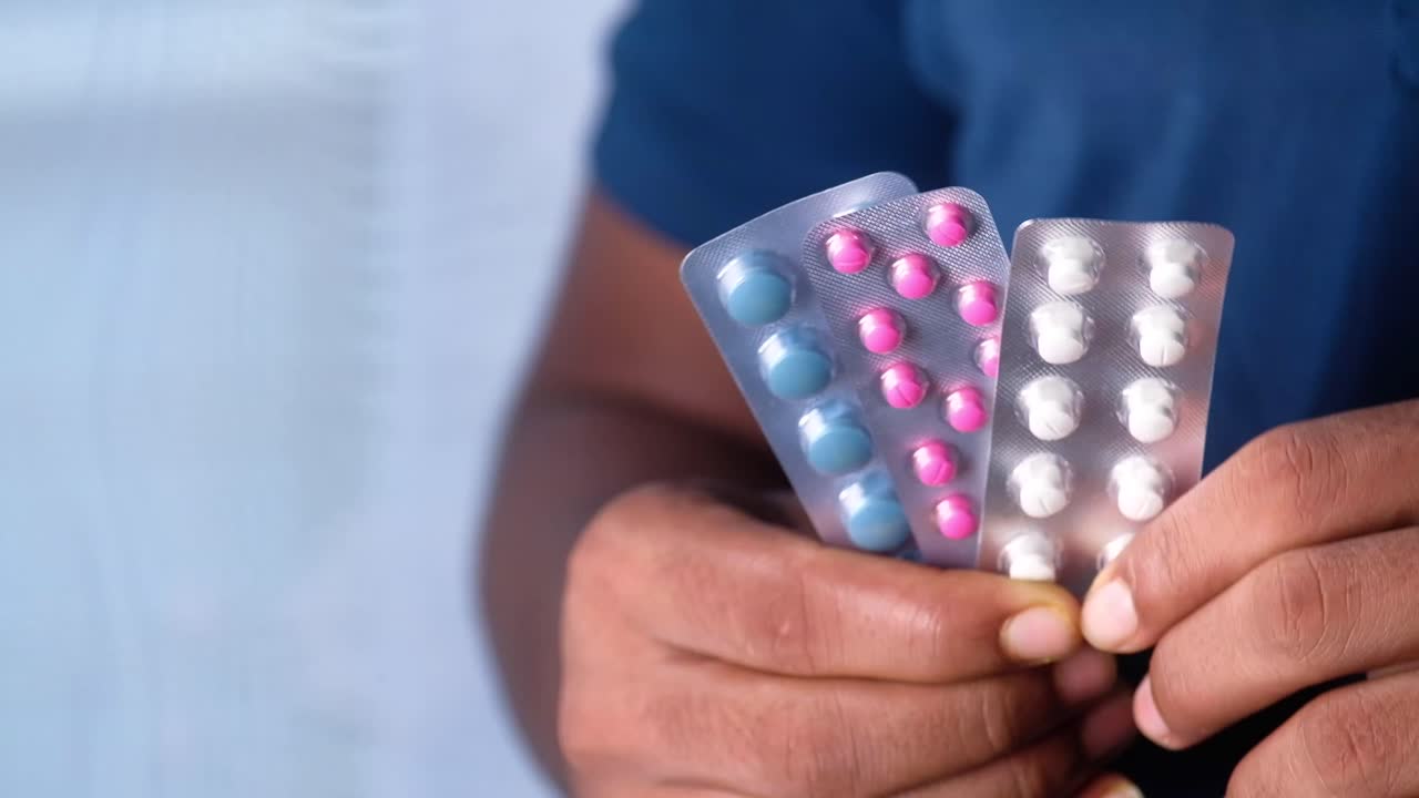 Person holding blister packs of various colored pills