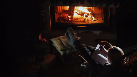 woman writes in a notebook while sitting by the fireplace