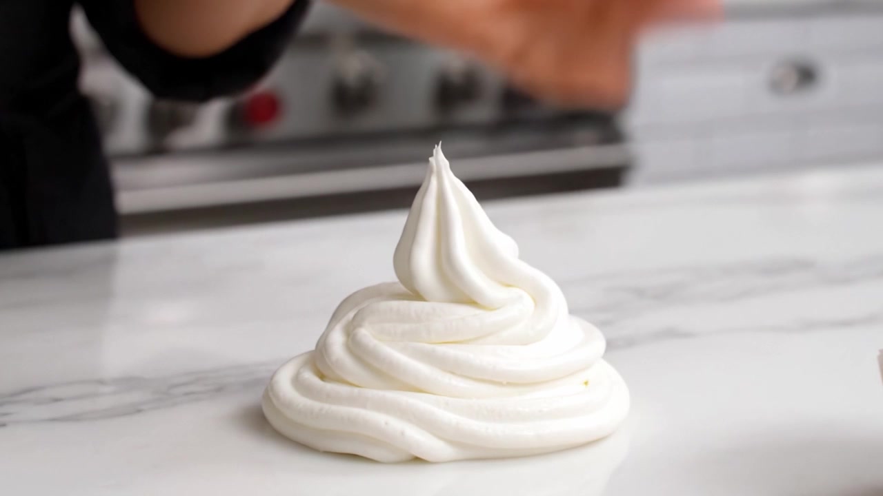 Dominando a arte de confeitar: criando belos redemoinhos de chantilly em uma superfície de mármore em um ambiente de cozinha moderna.
