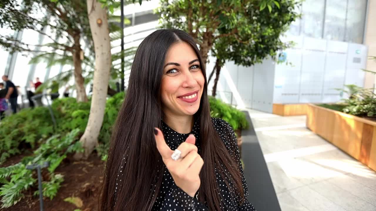 una mujer encantadora con el pelo largo señalando con el dedo a la cámara y sonriendo
