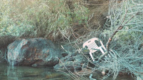 Plastic-chair-thrown-out-as-trash-along-seaside-shoreline