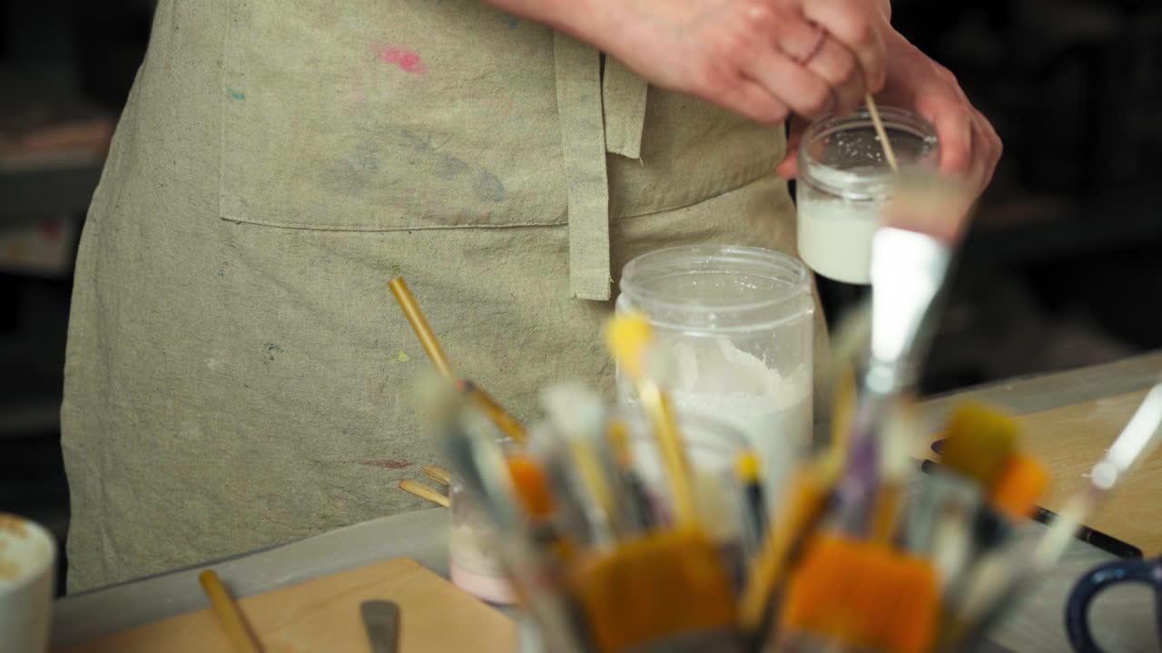 Female Artisan Mixing Glaze For Clay Cups At Workshop. closeup shot