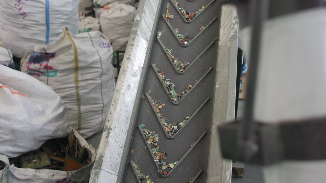 Conveyor Belt Carrying Plastic Fragments Closeup With Chevron Metal Plates And Scattered Multicolor Flakes . Media