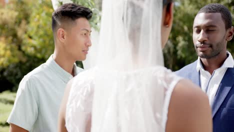 Hombre-Birracial-Oficiando-El-Matrimonio-De-Una-Feliz-Pareja-Afroamericana-En-Un-Jardín-Soleado,-En-Cámara-Lenta