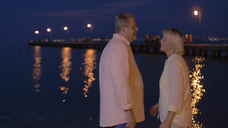 senior couple in love by the sea at night