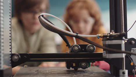 three unrecognizable pupils watching 3d printer working