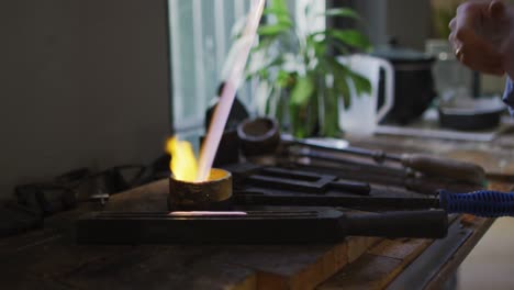 close up of hand of caucasian woman holding gas burner, melting metal for jewelry