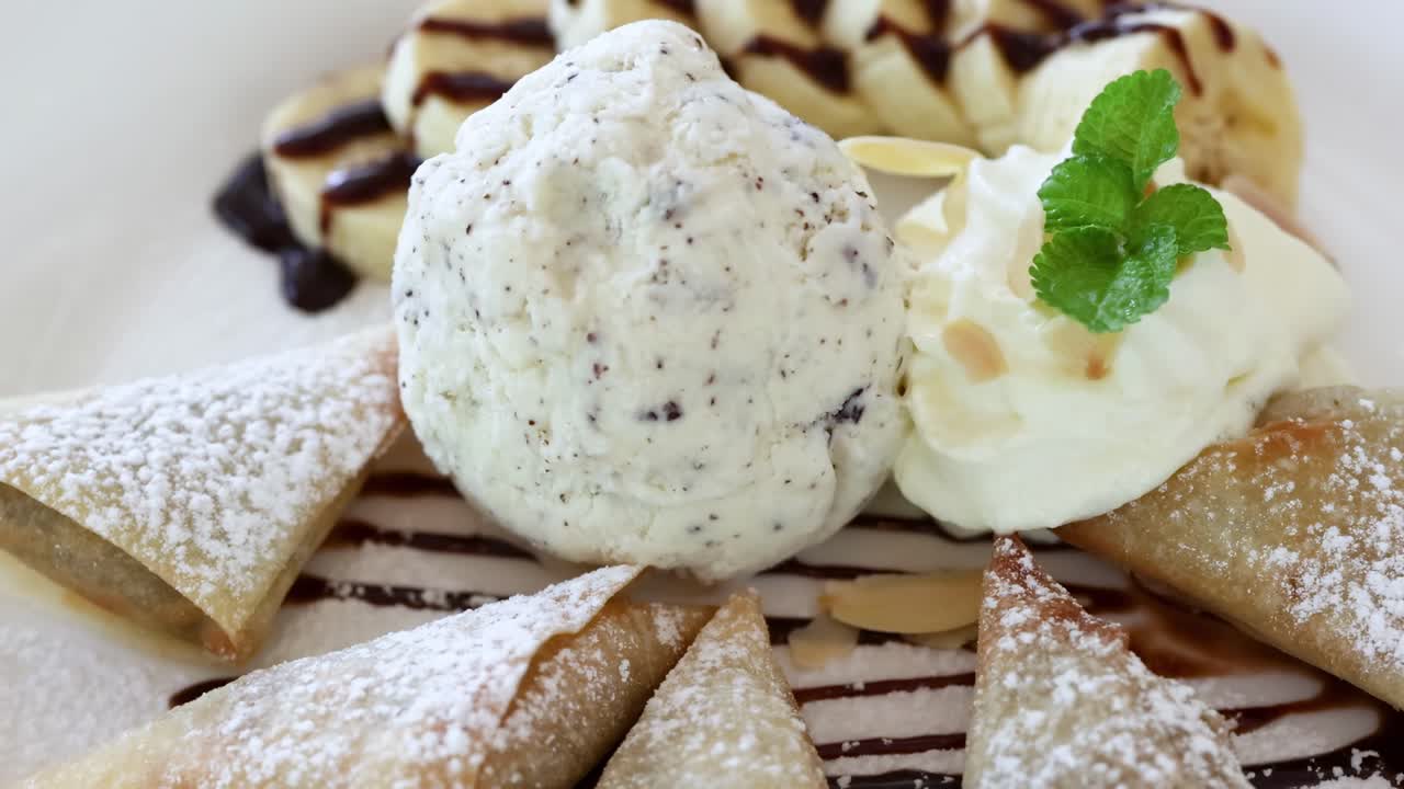 A beautifully plated dessert featuring mint garnish, chocolate drizzle, and powdered pastries.