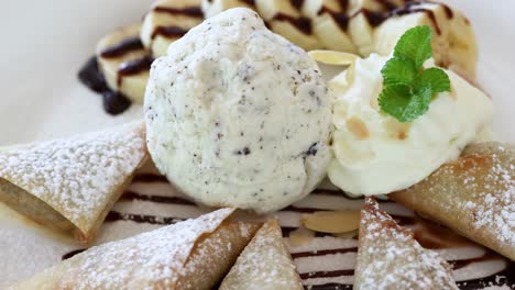 a beautifully plated dessert featuring mint garnish, chocolate drizzle, and powdered pastries.