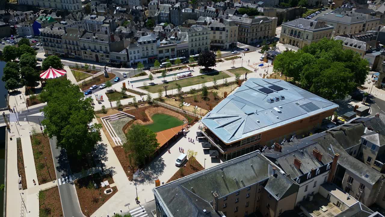 Drone pulling back from 11 Novembre Square, showing new market hall, geometric design, carousel and historic center of Laval. June 2025 - France
