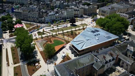 drone pulling back from 11 novembre square, showing new market hall, geometric design, carousel and historic center of laval. june 2025 - france