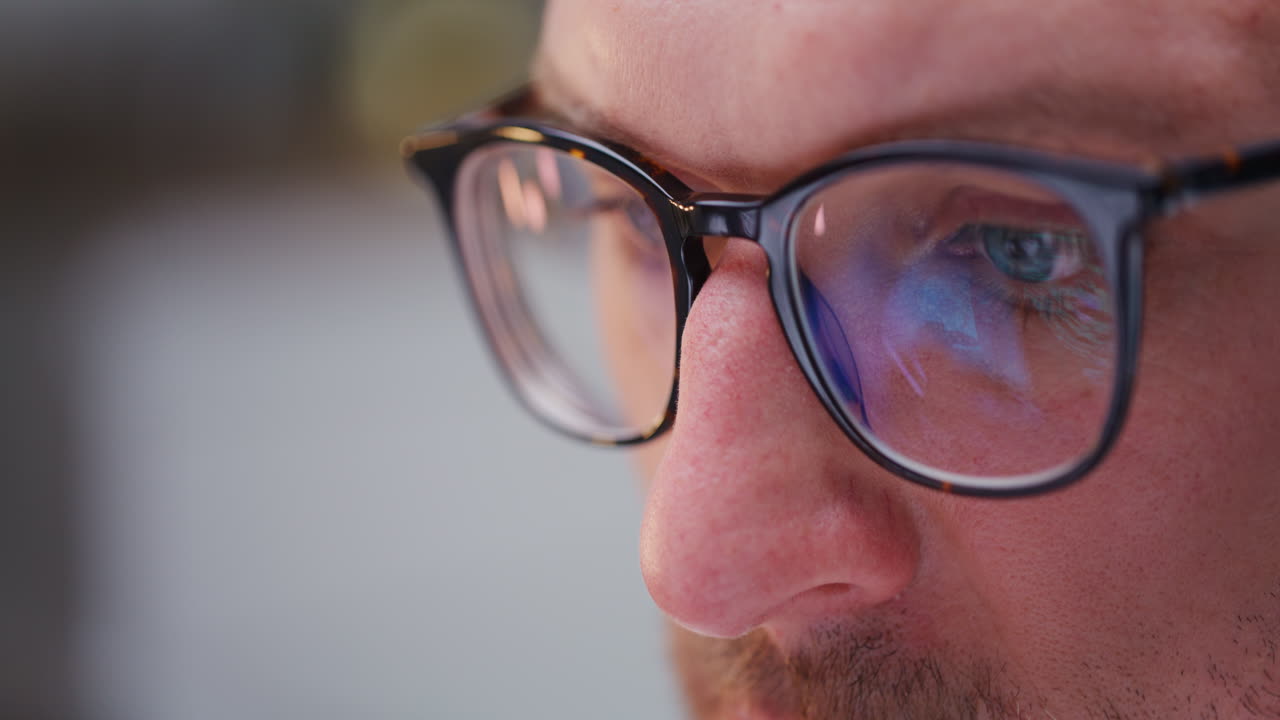 primer plano de la cara de un hombre con gafas trabajando en una computadora portátil