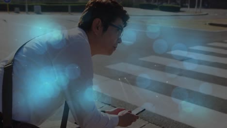 animation of shapes moving over asian man sitting and using smartphone