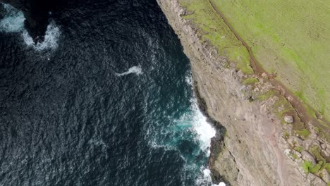 lago de levatnitis y acantilados en las islas feroe con tierra verde y océano, vista aérea