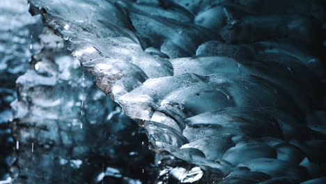 water drops slowly drip off melting ice inside of cave