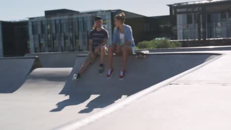 mujer y hombre caucásicos animando a su amigo de patinaje en un día soleado