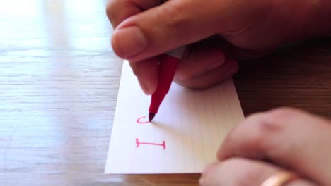 close up footage as male hands write a note using permanent marker pen on a small card of paper