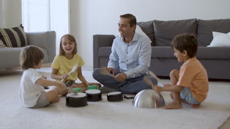 cute kids and dad sitting on carpet and playing with utensils