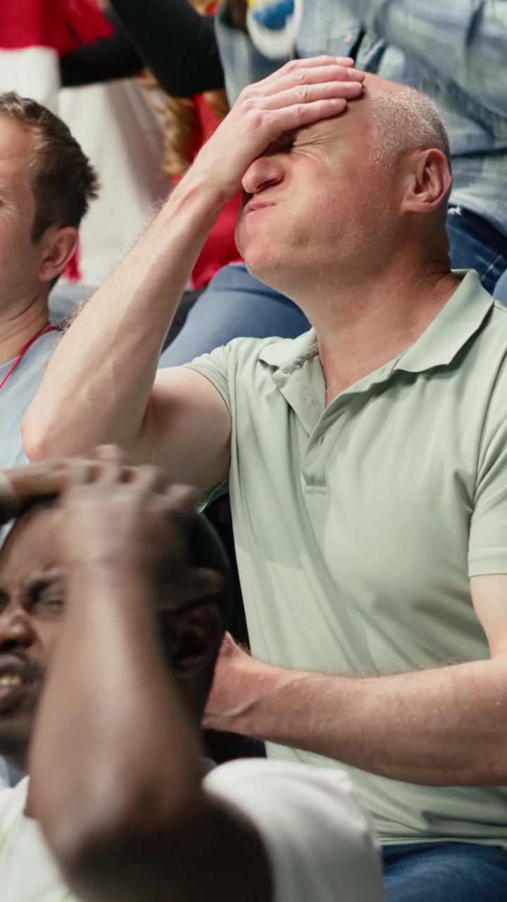 Vertikal video: Anspændt fodboldfan på stadiontribunen, der taber et live fodboldvæddemål.