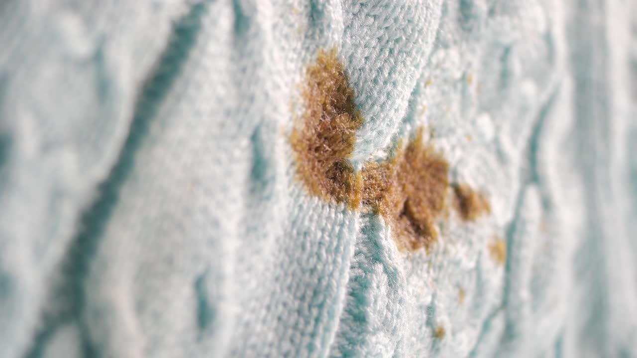 Detail hnědé skvrny na světle modré pletené látce