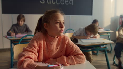 thoughtful student sitting at school desk. smiling girl answering questions