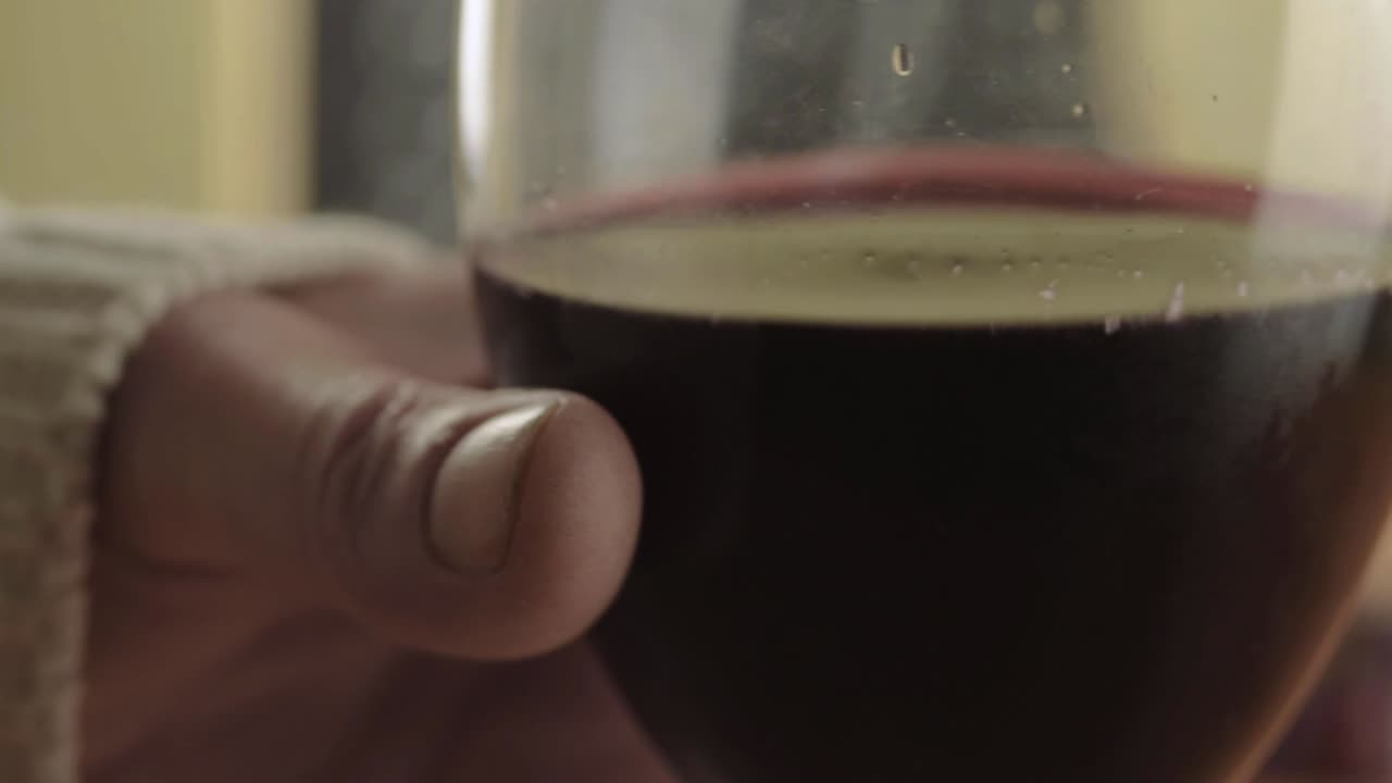 Mano che tiene un bicchiere di vino rosso da vicino