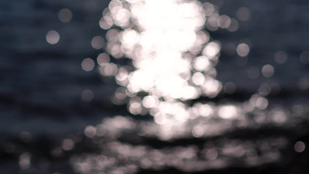 Abstract nature summer ocean sunset sea background. Small waves on water surface in motion blur with bokeh lights from sunrise. Holiday, vacation and recreational background concept. Slow motion