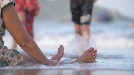 sea waves wash over elderly woman's feet and hands - relaxing on beach