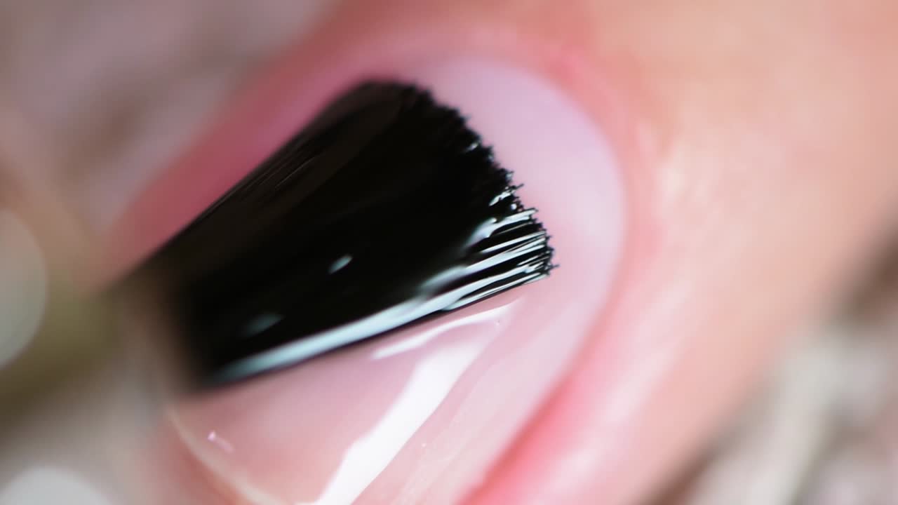 aplicación de la primera capa de esmalte de uñas transparente