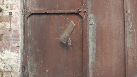 la vieja puerta de metal oxidada se cierra de golpe