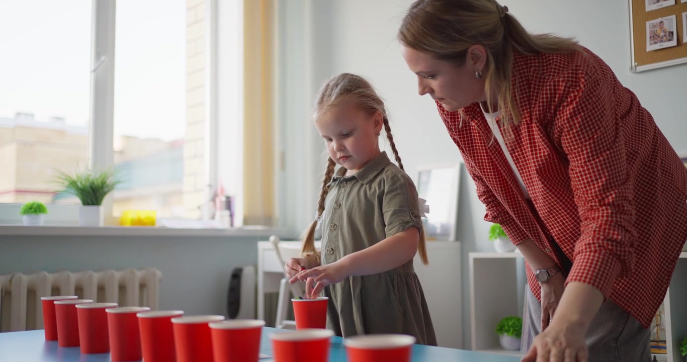 Teacher Guiding Young Girl in Educational Play Activity