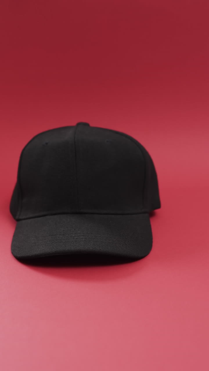 Vertical video of black baseball cap and copy space on red background