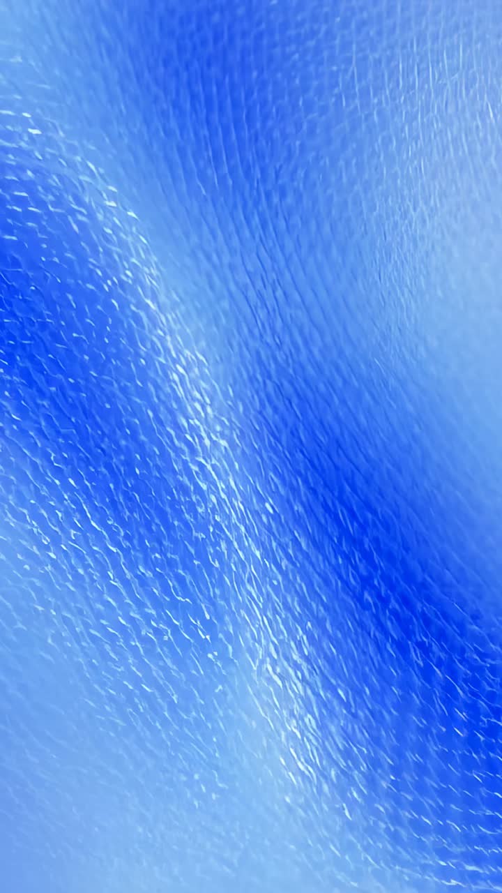 Vertical video: Shifting blue mesh ripple after seam appearing at left edge, looping wallpaper