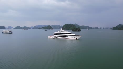 Panorámica-Aérea-A-Través-De-La-Proa-Del-Yate-De-Lujo-Blanco-En-La-Bahía-De-Ha-Long,-Vietnam,-Rodeada-De-Agua-Tropical