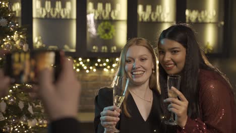 camera focuses on two friends dressed in elegant clothes at a new year's party, a friend takes a picture with a camera