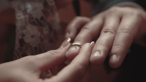 bride is putting an engagement ring on the finger of the groom during the wedding ceremony close-up slow motion